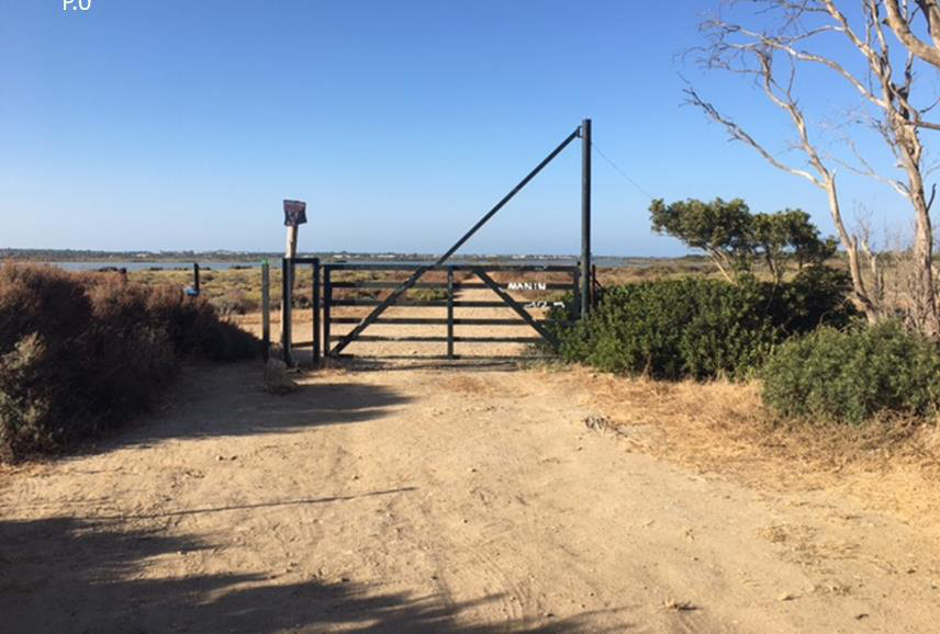 Portón metálico de entrada a la finca junto a un camino de tierra